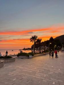 a group of people walking on the beach at sunset at Apartment Xenia in Petrovac na Moru