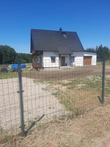 a house behind a fence in front of a house at Mazurska Sielanka in Orzysz