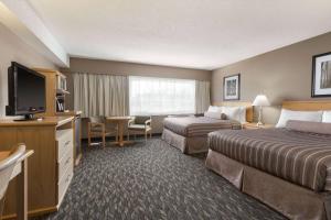um quarto de hotel com duas camas e uma televisão de ecrã plano em Travelodge by Wyndham Prince George em Prince George