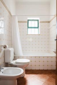 a bathroom with a toilet and a tub and a sink at Cerca Velha - Country House in Albufeira