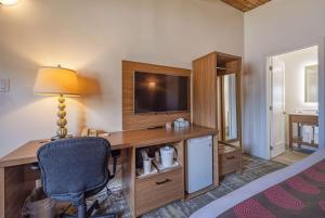 a bedroom with a desk with a television and a chair at Ramada by Wyndham Gananoque Provincial Inn in Gananoque