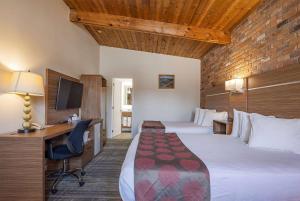 ガナノクエにあるRamada by Wyndham Gananoque Provincial Innのベッド2台とデスクが備わるホテルルームです。