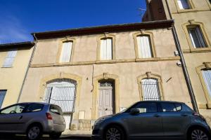 two cars parked in front of a building at Maison Eglantine YourHostHelper Classé 4* in Narbonne