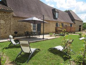 une terrasse avec une table, des chaises et un parasol dans l'établissement Gîte Val de Louyre et Caudeau, 3 pièces, 4 personnes - FR-1-616-282, à Saint-Alvère