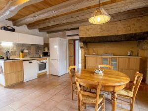 een keuken en eetkamer met een houten tafel en stoelen bij Gîte Val de Louyre et Caudeau, 3 pièces, 4 personnes - FR-1-616-282 in Saint-Alvère