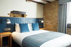 a bedroom with a large bed with blue pillows at Red Lion Hotel by Greene King Inns in Banbury
