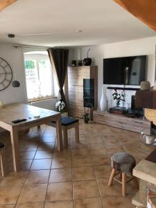 ein Wohnzimmer mit einem Tisch und einem TV in der Unterkunft Home Sweet Home by Stay Swiss in Courtedoux