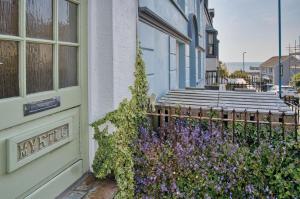 una puerta a una casa con flores púrpuras al lado en Myrtle - 1 Bedroom Apartment - Saundersfoot en Saundersfoot