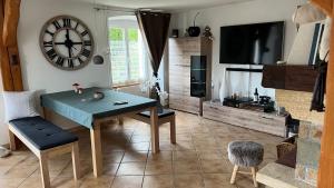 ein Wohnzimmer mit einem Tisch und einer Uhr an der Wand in der Unterkunft Home Sweet Home by Stay Swiss in Courtedoux