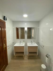 a bathroom with two sinks and two mirrors at Puerta del Sol - Plasencia in Plasencia