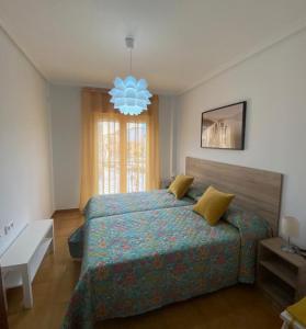 a bedroom with a large bed and a chandelier at Puerta del Sol - Plasencia in Plasencia