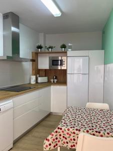 uma cozinha com armários brancos e uma mesa com um tapete estampado em Puerta del Sol - Plasencia em Plasencia