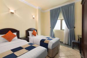 Howard Johnson Dammam Hotel في الدمام: غرفة فندقية بسريرين ونافذة
