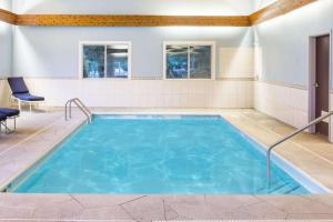 a large swimming pool with blue water in a room at Baymont by Wyndham Piqua in Piqua