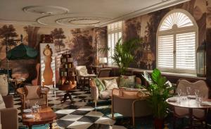 ロンドンにあるGreat Scotland Yard Hotel, part of Hyattの椅子とテーブル、壁画のある待合室