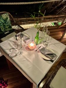 uma mesa com uma toalha de mesa branca e um vaso com uma vela em La Colonial Resort em El Nido