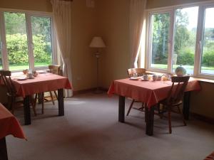 a dining room with two tables with red table cloths at Amber B&B in Ballyfarnon