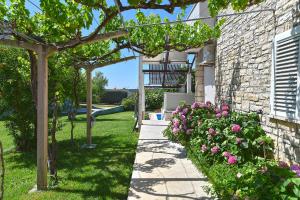 un jardín con flores rosas y un edificio de piedra en Double room with pool 2261, en Medulin