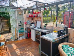 una cocina en un invernadero con fregadero y barra en Vrijstaande accommodatie Glamping de Kas InN, en Hank