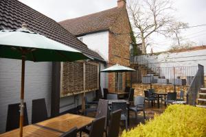 un patio con tavoli, sedie e ombrellone di Red Lion Hotel by Greene King Inns a Banbury
