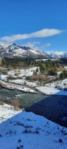 Un río con nieve y montañas al fondo. en Cabaña Challhuaco, en San Carlos de Bariloche