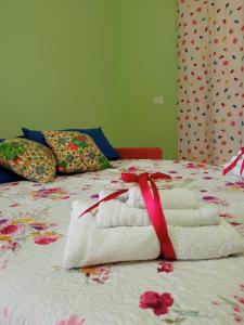 un mucchio di asciugamani su un letto con un nastro rosso di Rainbow Apartment a Scordia