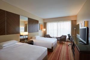a hotel room with two beds and a flat screen tv at Courtyard by Marriott Mumbai International Airport in Mumbai
