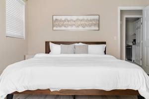 a white bedroom with a large white bed at Jacksonville Retreat: Unwind in Style at our Cozy Duplex Apartment in Jacksonville