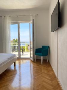 ein Schlafzimmer mit einem Bett, einem TV und einem blauen Stuhl in der Unterkunft Sea View Apartment in Hvar