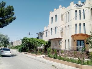 Un edificio blanco con un coche aparcado delante. en Hotel Al Hayit Teracce, en Bukhara