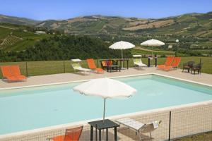 una piscina con sillas y sombrilla en L'Aurora B&B - Rural Villa With Private Pool & Panoramic View Near Montelparo, en Montelparo