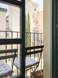 Duas cadeiras sentadas numa varanda com vista para uma janela em Modern apt in old town w cathedral views em Girona