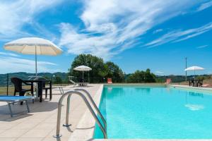 a swimming pool with a table and an umbrella at L'Aurora B&B - Rural Villa With Private Pool & Panoramic View Near Montelparo in Montelparo