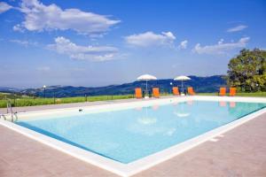 una piscina con agua azul y sillas naranjas en L'Aurora B&B - Rural Villa With Private Pool & Panoramic View Near Montelparo, en Montelparo