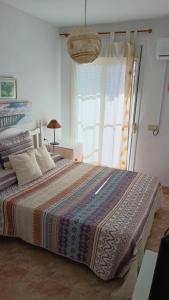 een slaapkamer met een groot bed met een deken erop bij La Casita de Nuria in Rincón de la Victoria