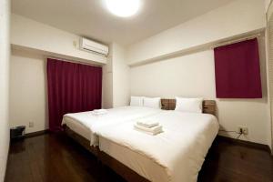 - une chambre avec un grand lit blanc et des rideaux rouges dans l'établissement PlusTom Stay-SHIMANOUCHI-, à Osaka