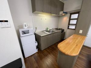 uma pequena cozinha com um lavatório e um micro-ondas em PlusTom Stay-SHIMANOUCHI- em Osaka
