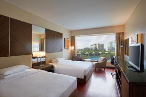 um quarto de hotel com duas camas e uma televisão de ecrã plano em Courtyard by Marriott Mumbai International Airport em Mumbai