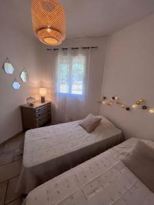 a bedroom with two beds and a window and a chandelier at Appartement rénové tout confort 10mn de Campomoro in Grossa