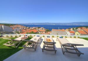 a patio with tables and chairs and a view of the city at Villa Bella Vista in Vrbnik