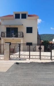 Uma casa branca com uma cerca preta à frente. em Apartmani Elisa em Stari Grad