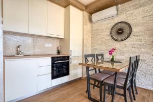 a kitchen with white cabinets and a wooden table and chairs at Apartmani Nikic Tivat in Tivat