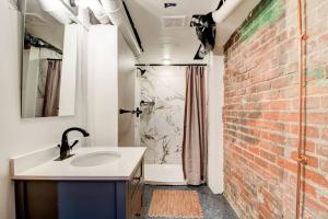 a bathroom with a sink and a brick wall at The Underground by East Grand in Detroit