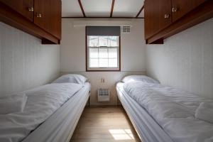 two beds in a small room with a window at 80, Midden in de natuur - Airco! in Oisterwijk