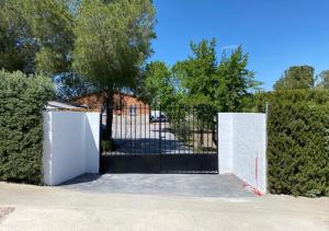 a gate in front of a fence with trees at Casa con piscina, Villa Alarilla in Fuentidueña de Tajo