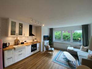 a kitchen with white cabinets and a living room at Townhouse Am Kurpark - ruhig und zentral inklusive Wäschepaket & Parkplatz in Braunlage