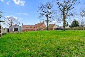 a large green field with a house and trees at Cosy 2 bed with parking and garden in Cawston
