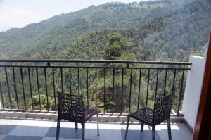 two chairs on a balcony with a view of a mountain at Summer Hill Resort in Chail