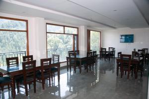 a dining room with tables and chairs and windows at Summer Hill Resort in Chail