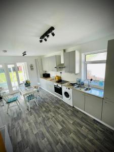 a kitchen with white cabinets and a table and chairs at Dot's Escape - 2 bed bungalow. in Kent